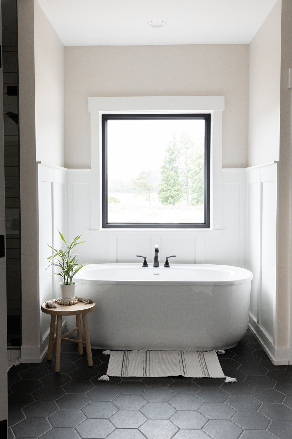 Freestanding tub with large window and black fixtures in a West Michigan bathroom remodel by Ridgewood Home Construction