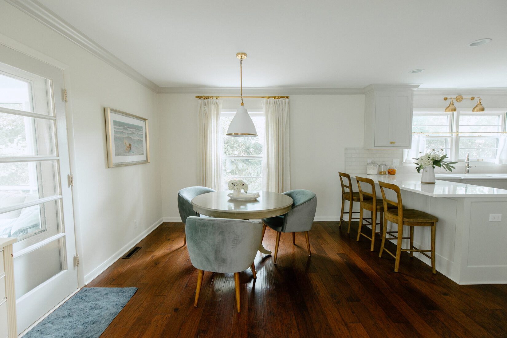 Cozy dining nook with round table and velvet chairs next to remodeled kitchen in West Michigan by Ridgewood Home Construction
