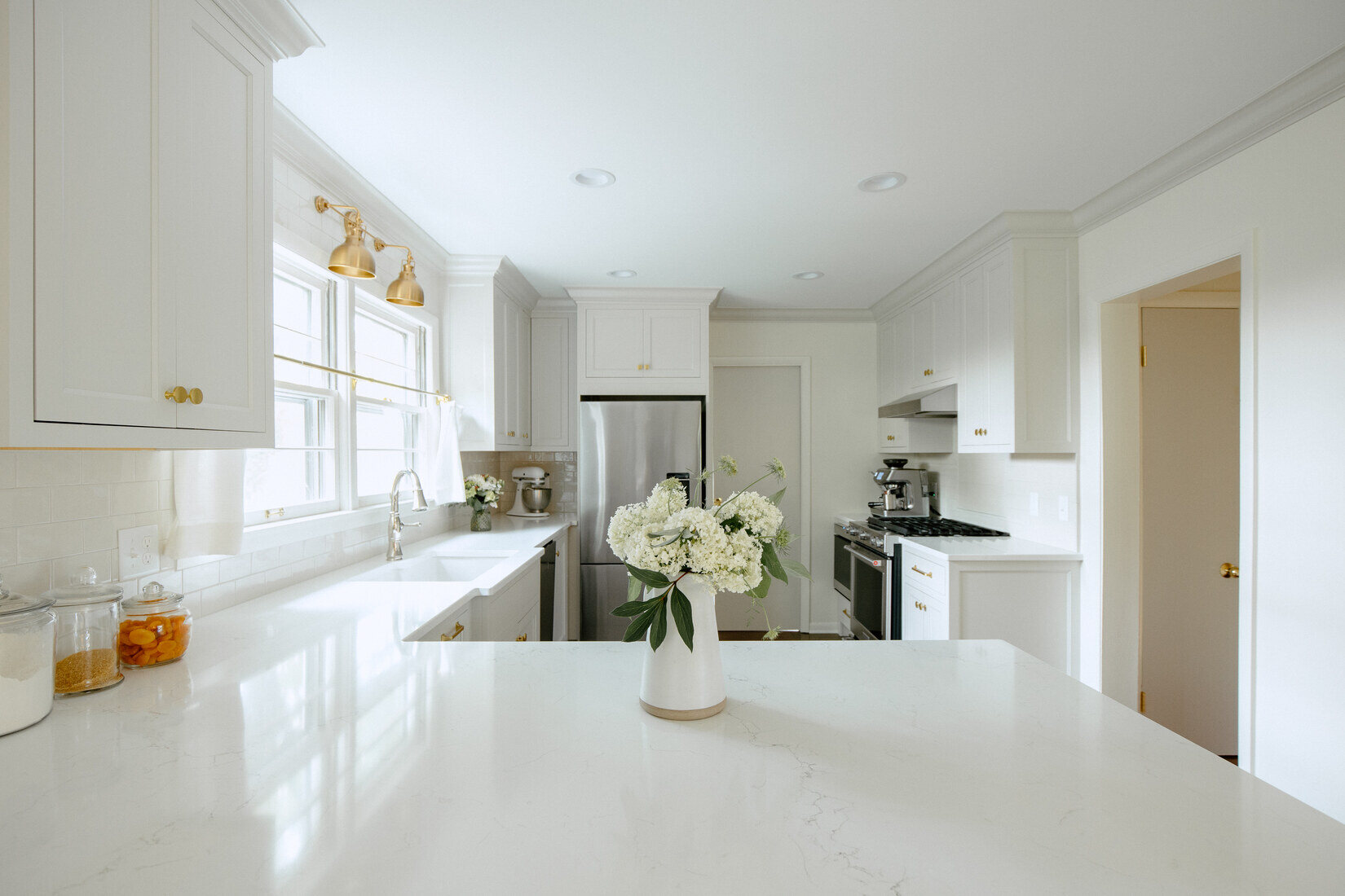 White kitchen with floral centerpiece and stainless appliances in West Michigan by Ridgewood Home Construction