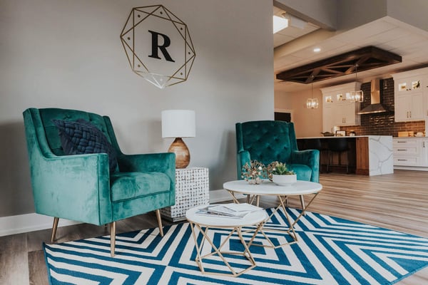 Stylish seating area in Ridgewood Home Construction’s Grand Rapids, MI showroom featuring modern emerald green chairs and geometric decor