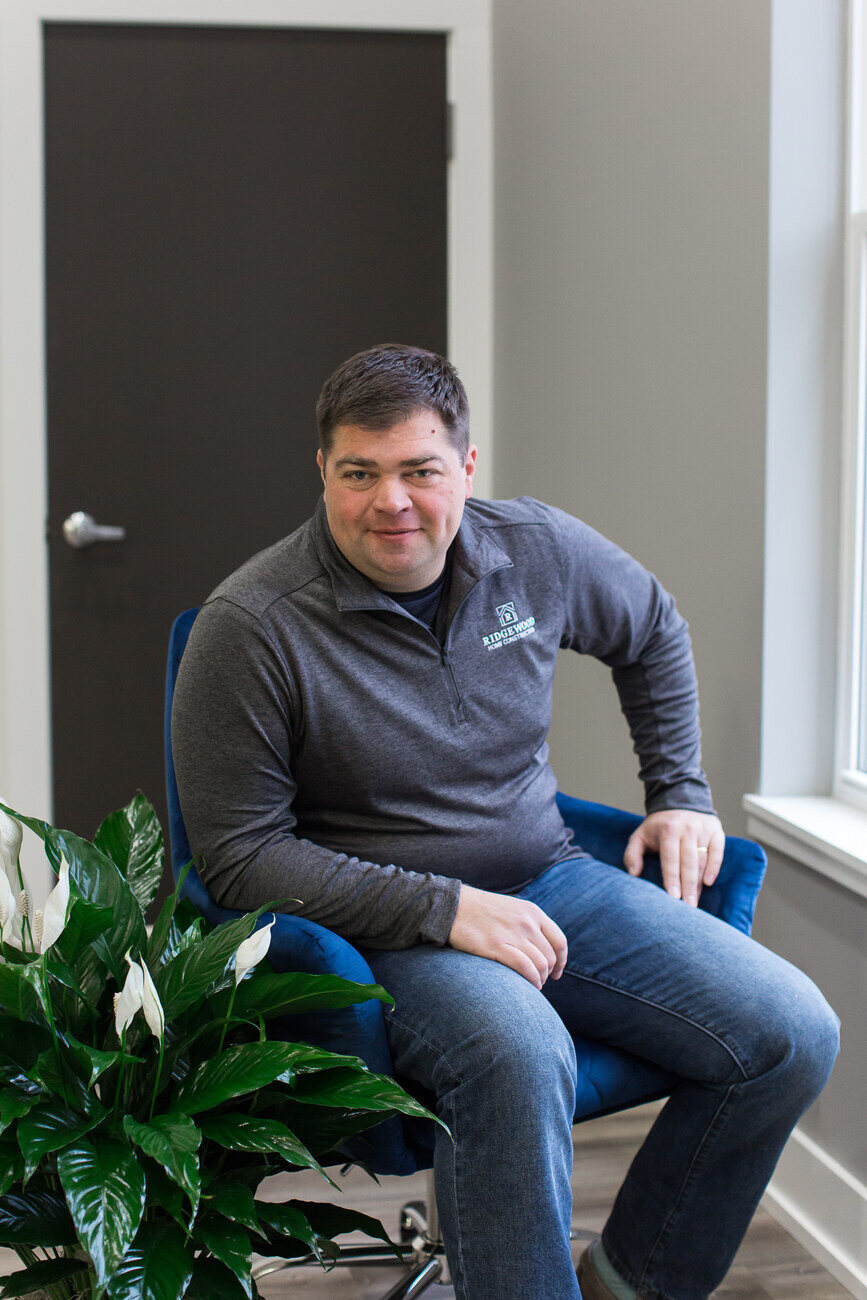 Rich from Ridgewood Home Construction seated near a plant in Grand Rapids, MI showroom