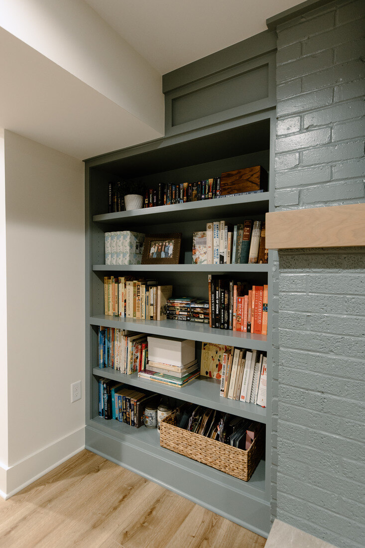 Built-in bookshelf painted sage green in a Grand Rapids basement remodel by Ridgewood Home Construction