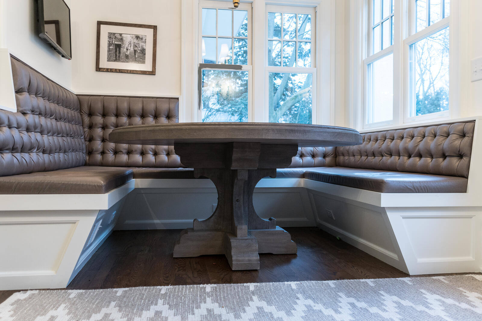 Cozy breakfast nook remodel with tufted bench seating and round wood table by Ridgewood Home Construction in East Grand Rapids