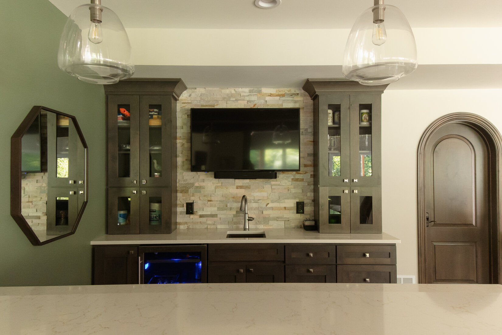 Basement wet bar remodel with dark cabinetry and stone backsplash by Ridgewood Home Construction in Grand Rapids Township