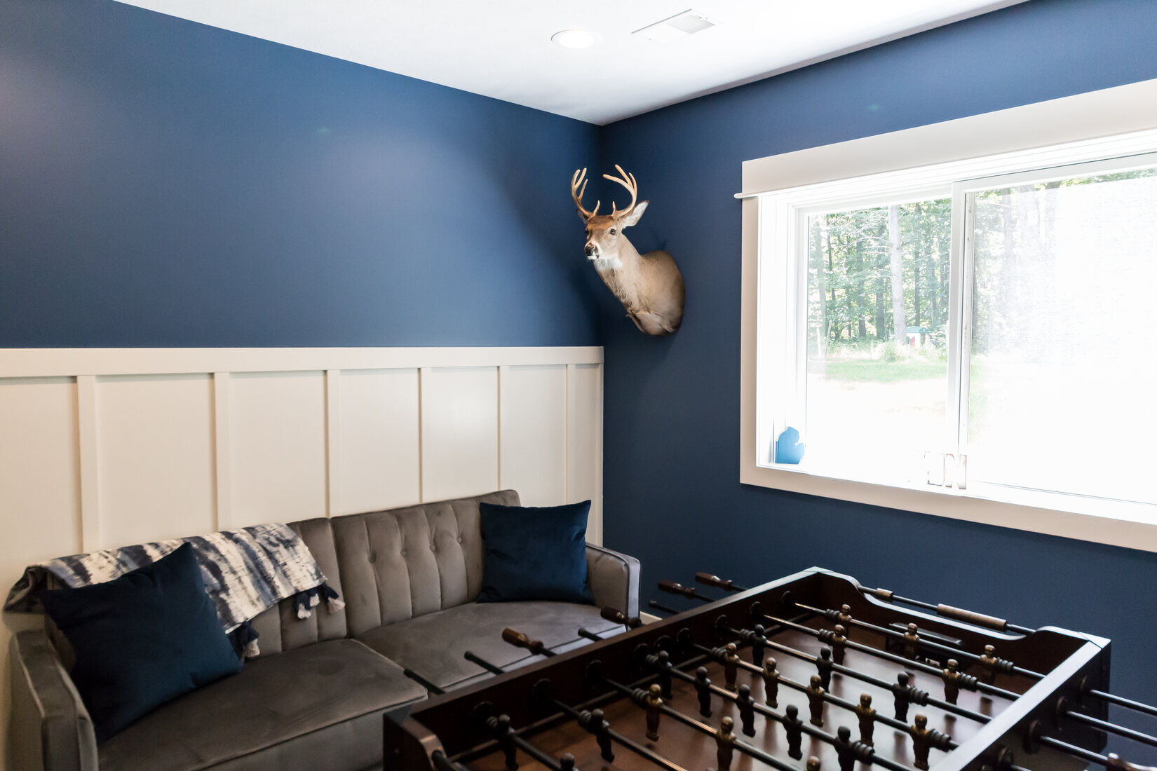 Basement game room with blue accent wall and foosball table in Sparta, MI by Ridgewood Home Construction