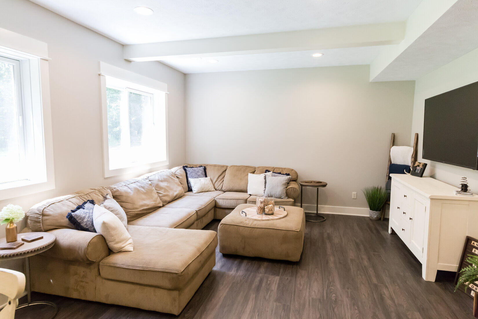 Cozy basement living room in Sparta, MI with sectional sofa and neutral tones by Ridgewood Home Construction