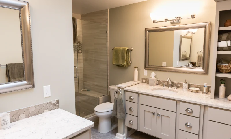 A modern bathroom in Grand Rapids, MI, with a glass shower, toilet, large mirror, white cabinets, and light countertops; towels and toiletries are neatly arranged to refresh the space.