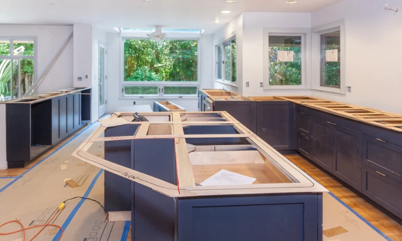 A modern kitchen refresh in progress in West Michigan, with blue cabinets, countertops not yet installed, and construction materials scattered on the floor.