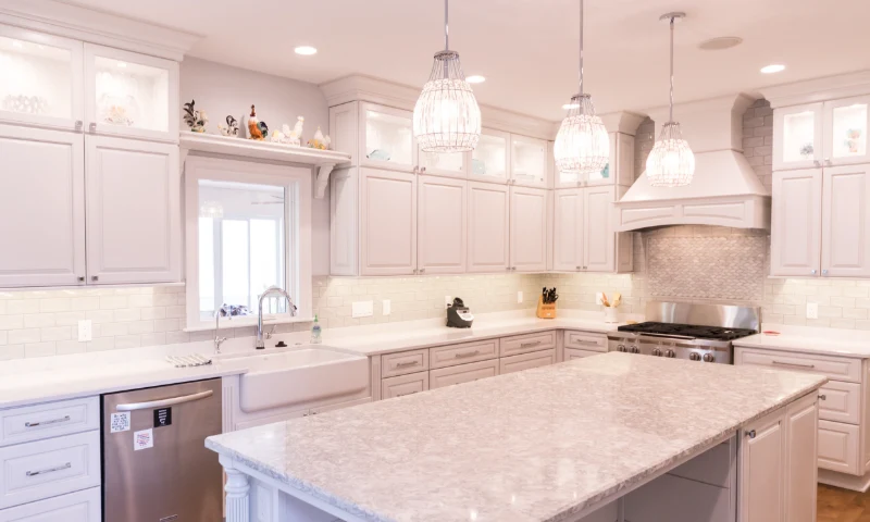 A modern kitchen in Grand Rapids, Michigan, with light gray cabinets, a large marble island, stainless steel appliances, pendant lights, and a farmhouse sink—perfect for a quick refresh to your home’s style.