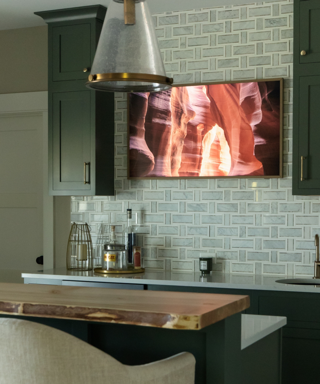 Satkoski – 43 A kitchen with dark green cabinets, a marble-patterned tile backsplash, a wooden bar counter, and a wall-mounted picture of a canyon—part of a stunning Byron Center Whole Home Remodel.